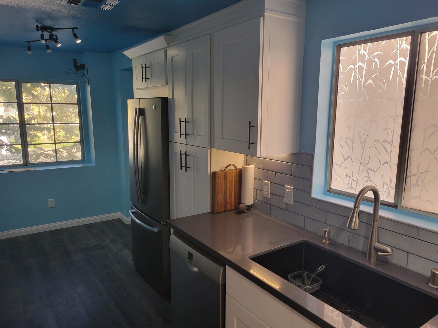 A kitchen with blue walls and white cabinets.